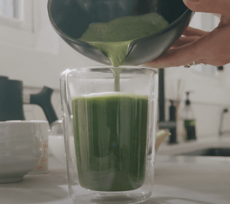Matcha tea shot being poured over Sensa infused tea in glass cup.